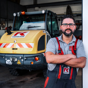 KASSECKER Mitarbeiter Maschinentechnik Eine Person in KASSECKER Arbeitskleidung steht neben einem Radlader in einer Garage.